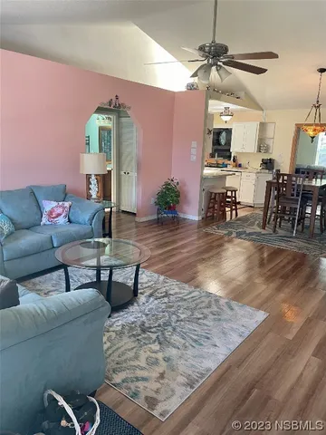 a view of a dining room and livingroom with furniture wooden floor a chandelier