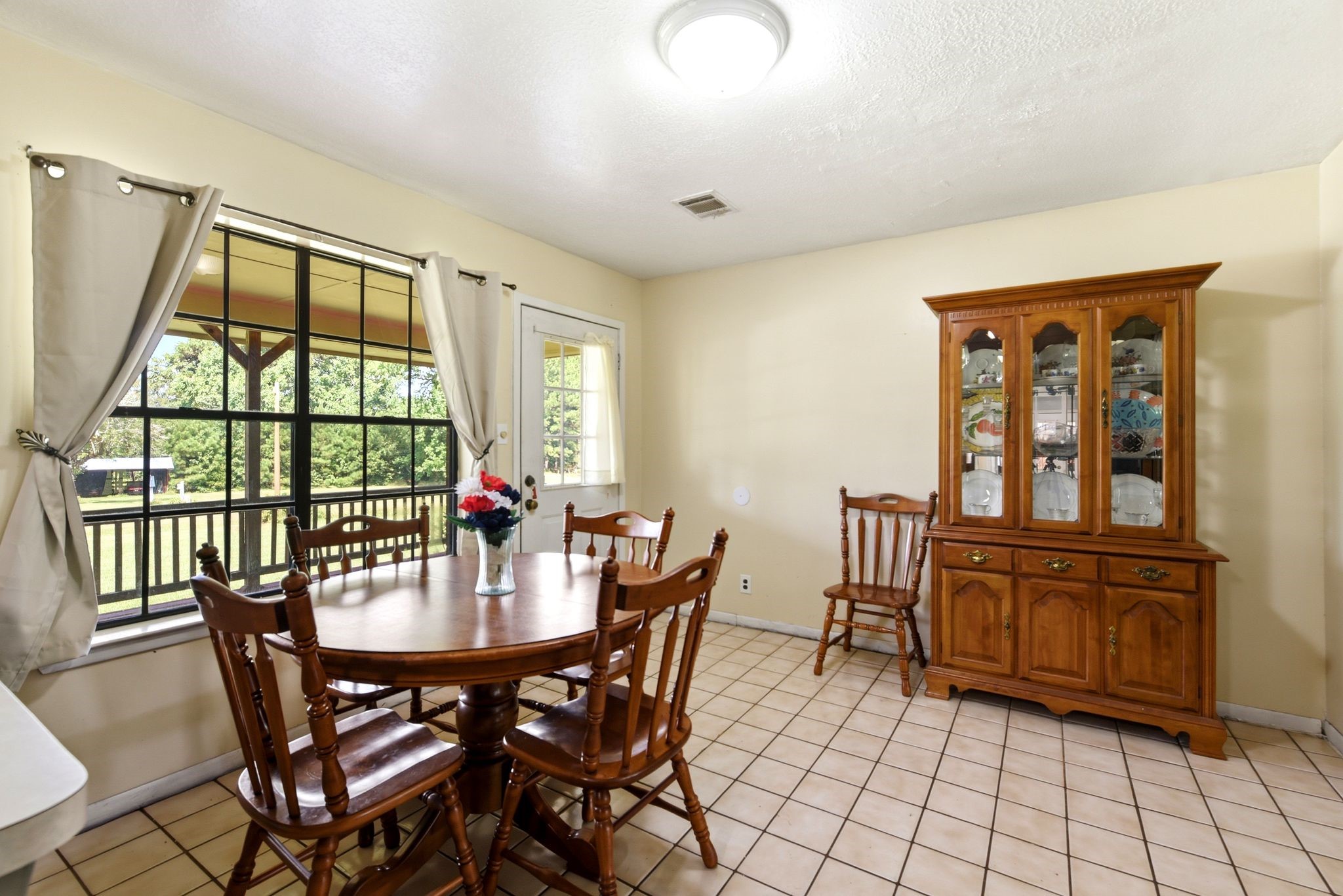 151 Parker Road New Waverly, TX 77358 - Photo 11 of 36 Charming dining area with large windows offering scenic views, complemented by a classic wooden table set and a matching china cabinet.