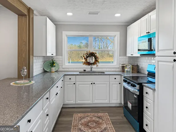 a kitchen with stainless steel appliances granite countertop a stove a sink and a microwave