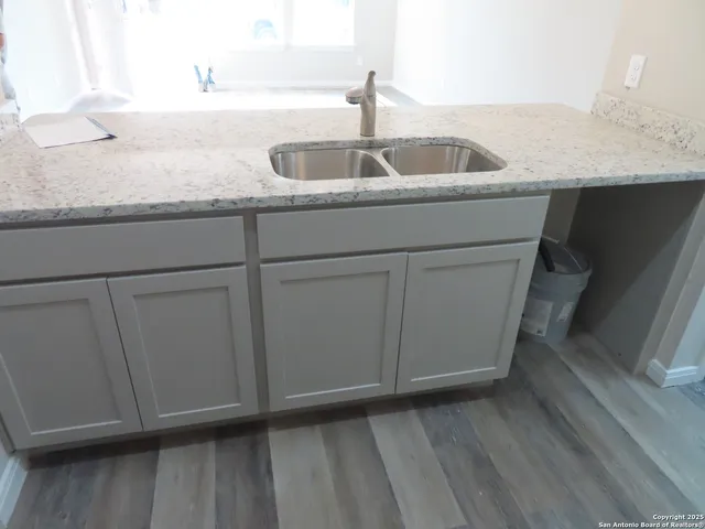 a kitchen with granite countertop white cabinets and sink