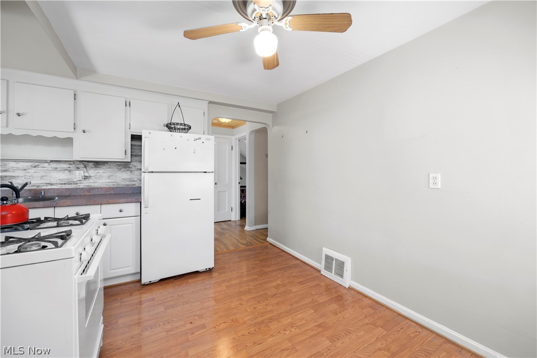 3305 Warren Road Cleveland, OH 44111 - Photo 12 of 28 Kitchen with ceiling fan, white cabinets, white appliances, backsplash, and light wood-type flooring