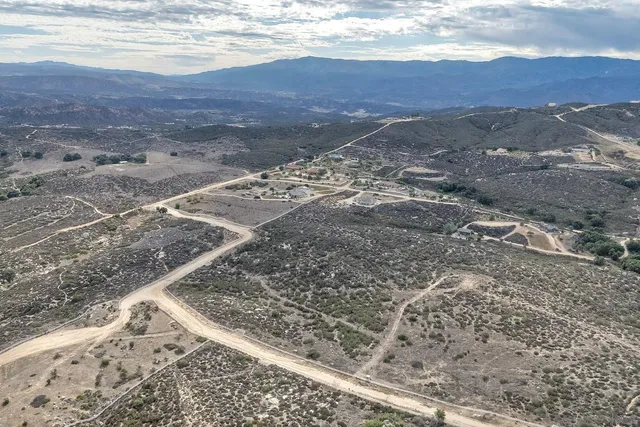 a view of a dry yard with mountains in the background