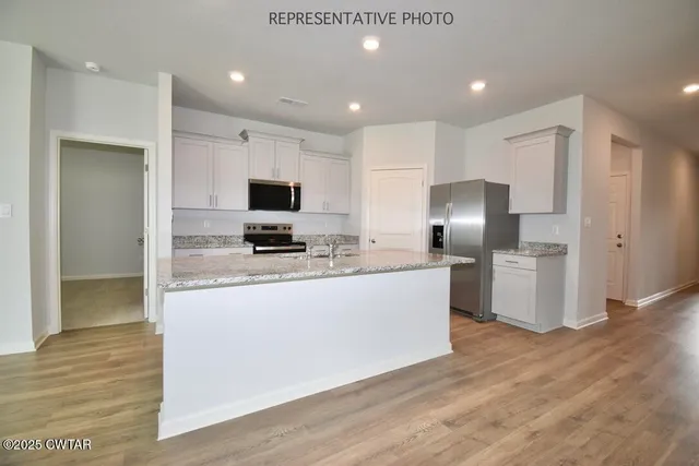 a large kitchen with stainless steel appliances granite countertop a stove a sink and a refrigerator