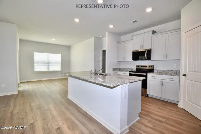 a kitchen with kitchen island granite countertop a sink appliances cabinets and wooden floor