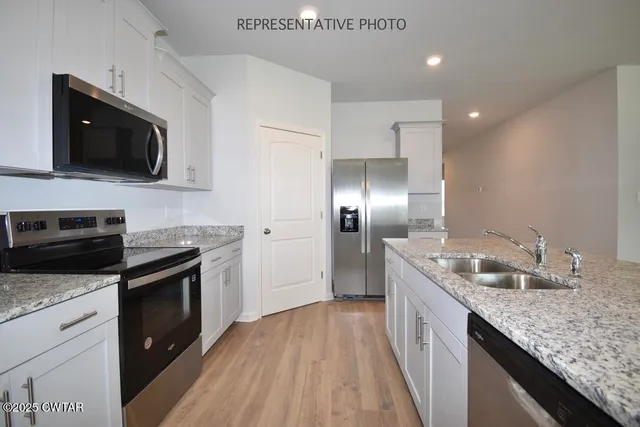 a kitchen with stainless steel appliances granite countertop a sink a stove top oven and wooden floor