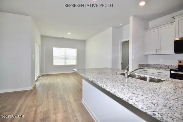 a kitchen with a sink granite counter tops and a stove with kitchen island