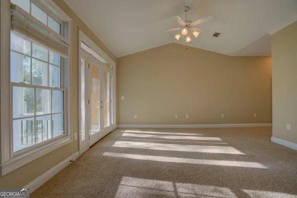 a view of an empty room with a fireplace and chandelier fan