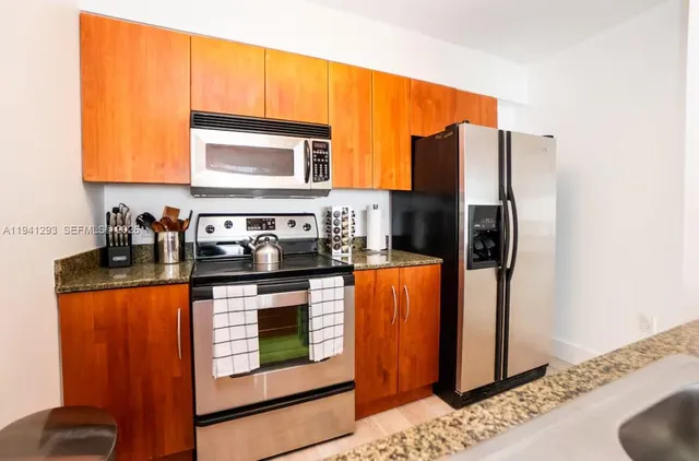 a kitchen with stainless steel appliances granite countertop a refrigerator a stove and a sink