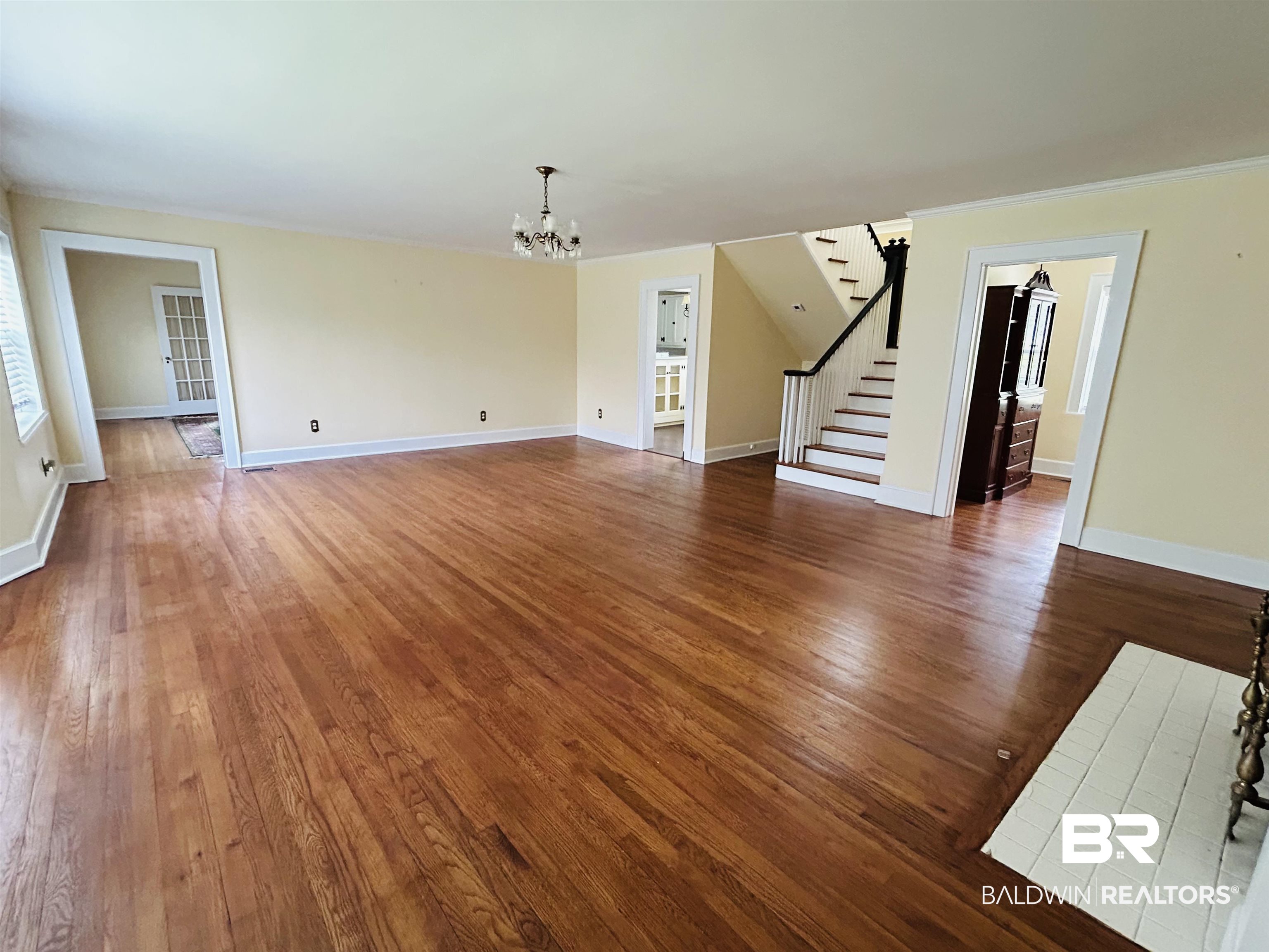 1405 Escambia Avenue Brewton, AL 36426 - Photo 2 of 16 Unfurnished living room with a chandelier, stairs, wood finished floors, and crown molding