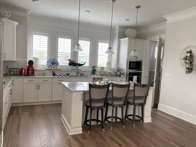 a kitchen with a sink stove and white cabinets with wooden floor