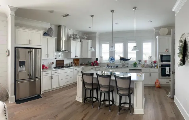 a kitchen with stainless steel appliances granite countertop a refrigerator a stove a sink dishwasher a dining table and chairs with wooden floor