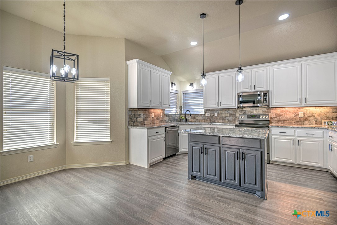 3106 Pitchfork Circle Belton, TX 76513 - Photo 10 of 45 a kitchen with granite countertop wooden floors stainless steel appliances and white cabinets