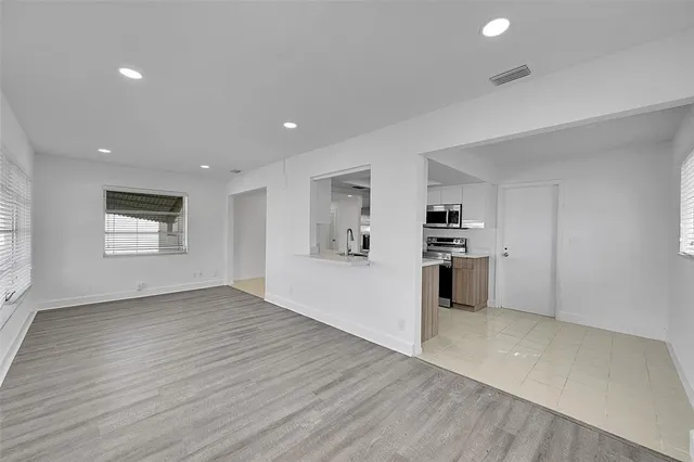 an empty room with wooden floor and kitchen