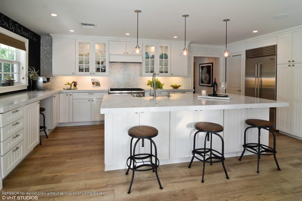 200 Colony Road Jupiter Inlet Colony, FL 33469 - Photo 8 of 26 a kitchen with stainless steel appliances kitchen island granite countertop a dining table chairs sink and white cabinets