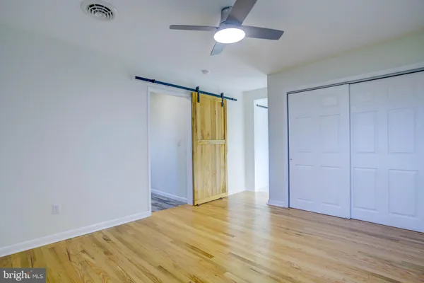 a view of a bedroom with wooden floor and a ceiling fan