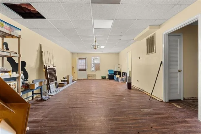 an empty room with wooden floor chandelier fan and windows