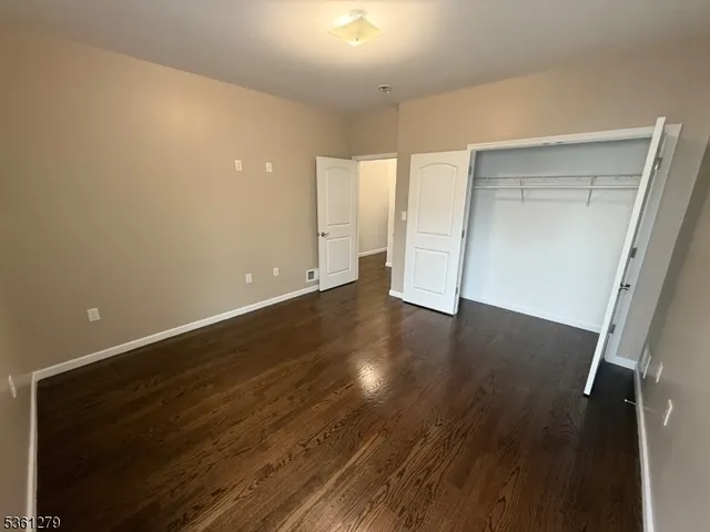 an empty room with wooden floor and closet