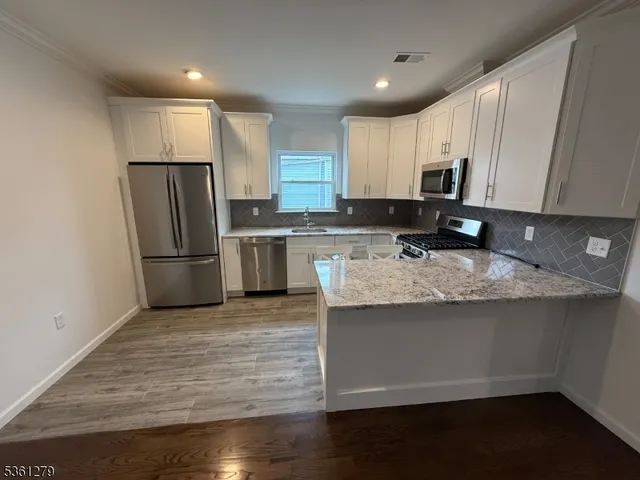 a kitchen with stainless steel appliances granite countertop a stove refrigerator sink and microwave