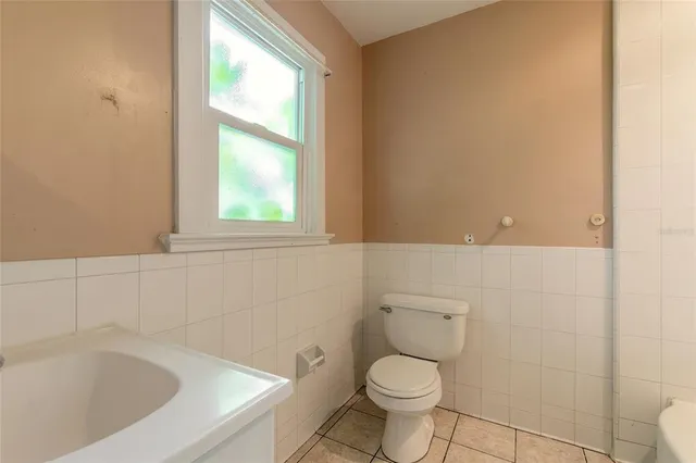 an empty room with wooden floor chandelier fan and windows