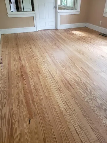 a view of empty room with window and wooden floor