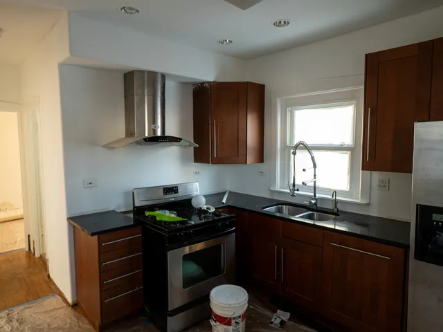 a kitchen with stainless steel appliances granite countertop a sink a stove cabinets counter space and a window