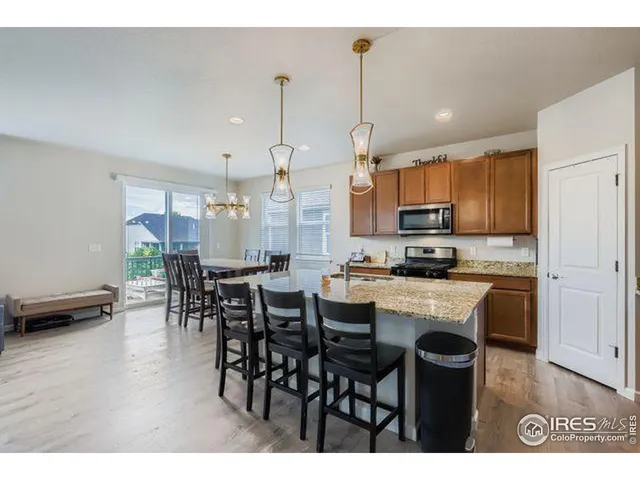 a open kitchen with stainless steel appliances kitchen island granite countertop a table chairs and a stove