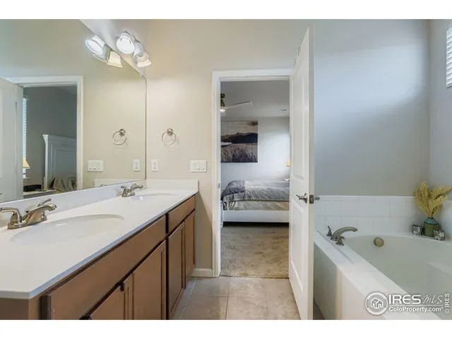 a en suite bathroom with a granite countertop sink and a bathtub