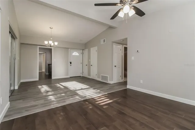 a view of an empty room and chandelier fan