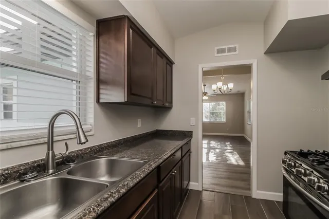 a kitchen with granite countertop a sink stainless steel appliances and cabinets