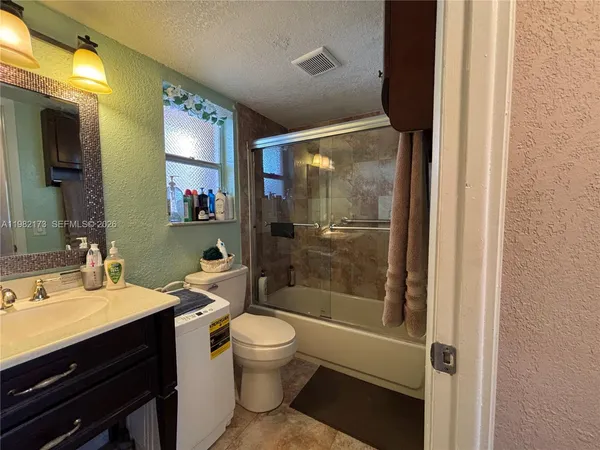 a bathroom with a granite countertop sink a toilet and shower