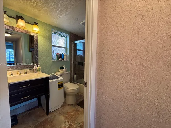 a view of a hallway with wooden floor and a bathroom