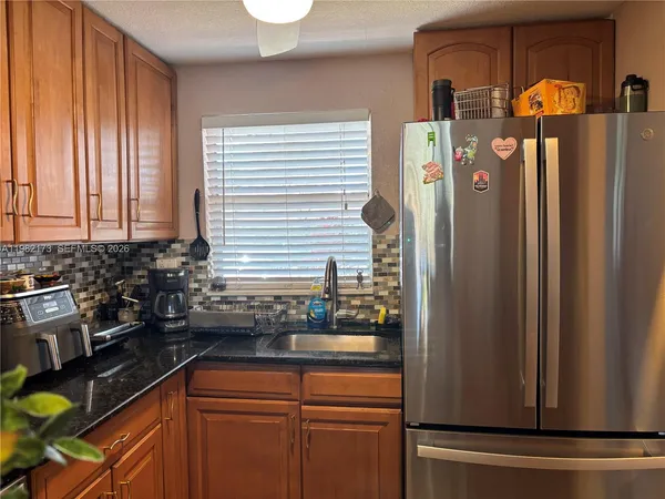 a kitchen with stainless steel appliances granite countertop a refrigerator and a sink