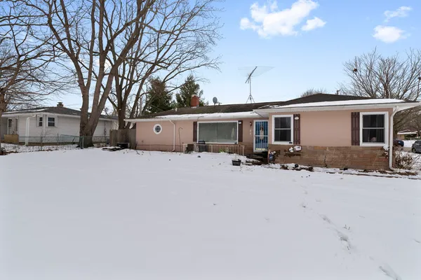 a front view of house with yard and trees in the background