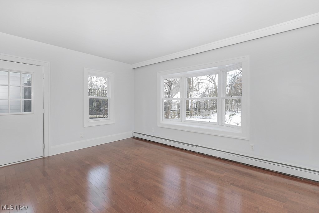 2596 Ashton Road Cleveland, OH 44118 - Photo 20 of 43 Unfurnished room with dark hardwood / wood-style floors, a healthy amount of sunlight, and a baseboard radiator