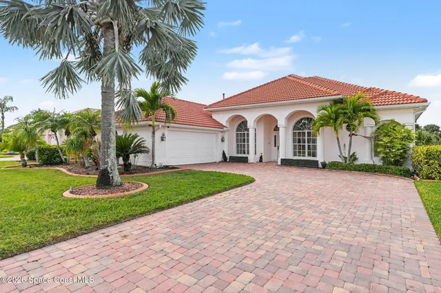 a front view of a house with a garden and palm trees
