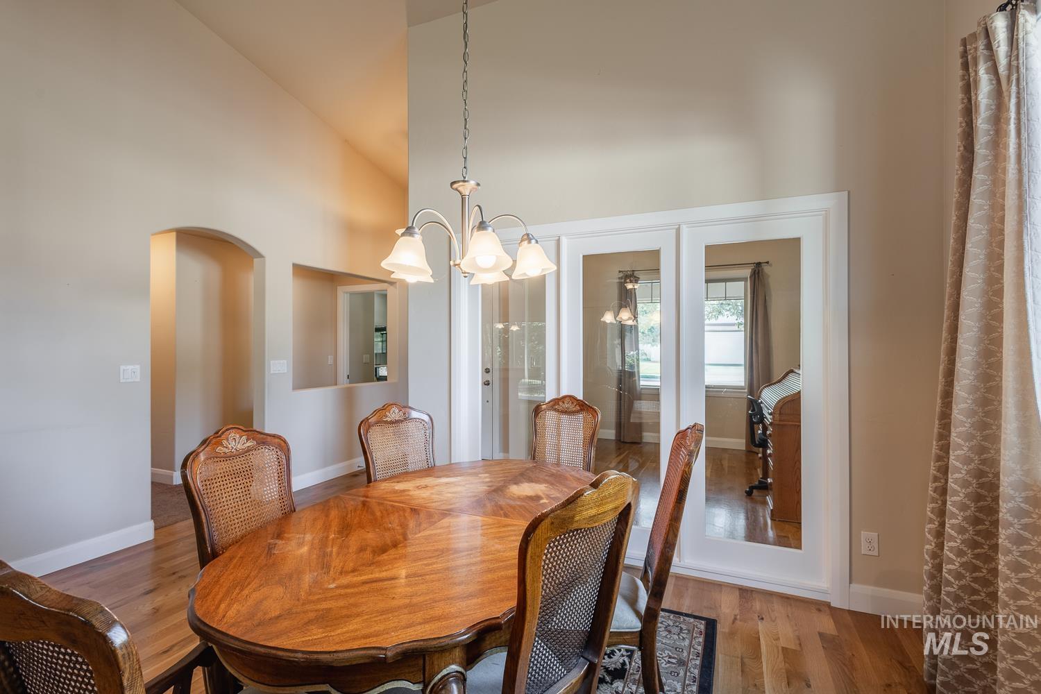 1186 East Observation Street Meridian, ID 83642 - Photo 17 of 33 Formal dining area featuring vaulted ceilings, wood-finish flooring, a pass-through window, an arched doorway, and double French doors with transom windows