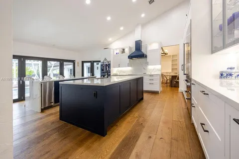 a large kitchen with stainless steel appliances a large counter top a stove and a wooden floors