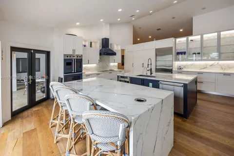 a kitchen with stainless steel appliances granite countertop a sink a stove a refrigerator and island with wooden floor