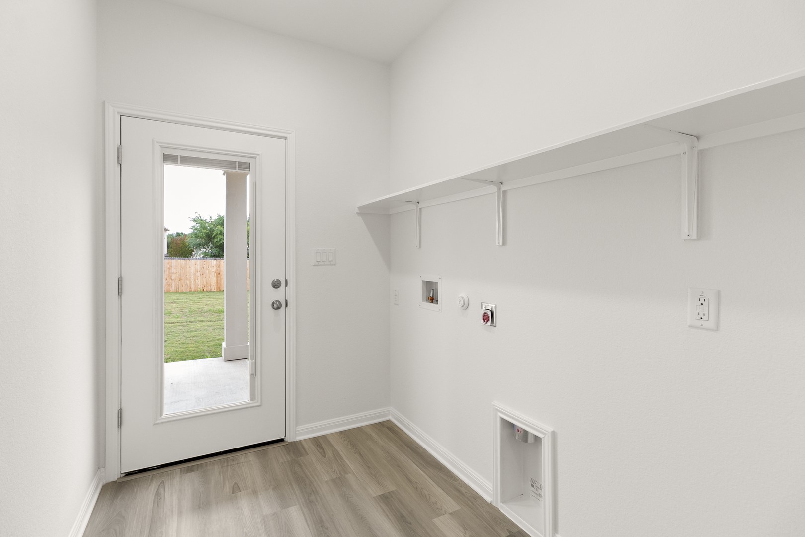 18605 Emu Lane Manor, TX 78653 - Photo 17 of 27 Utility area featuring light wood-style flooring, white walls, and an exterior door providing access to the yard
