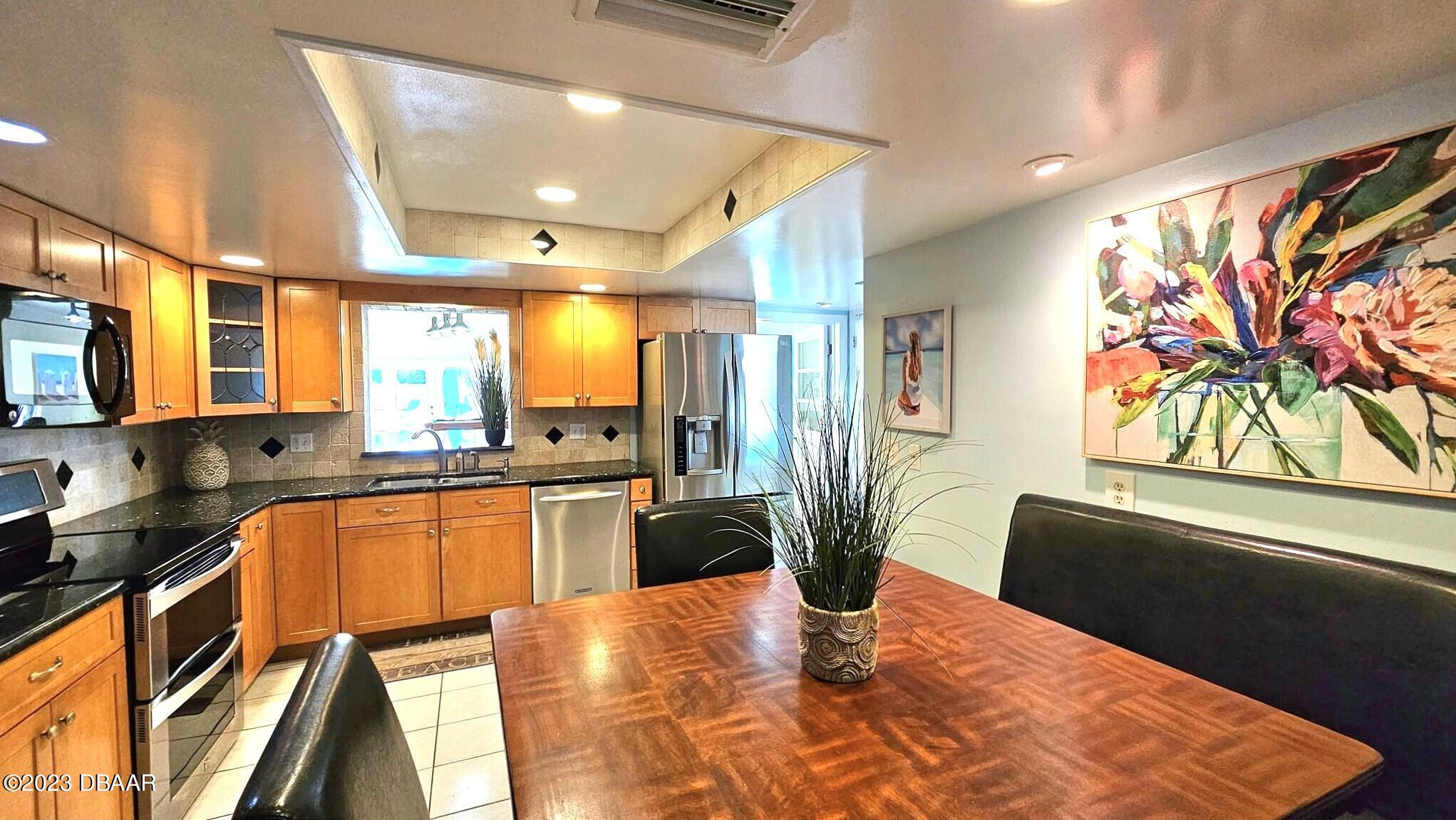 6 Sunrise Avenue Ormond Beach, FL 32176 - Photo 38 of 83 a kitchen with stainless steel appliances granite countertop a refrigerator a stove a sink a dining table and chairs with wooden floor