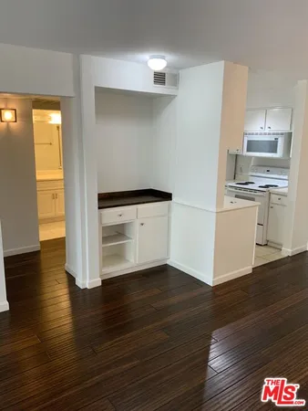 a kitchen with a stove a refrigerator and white cabinets