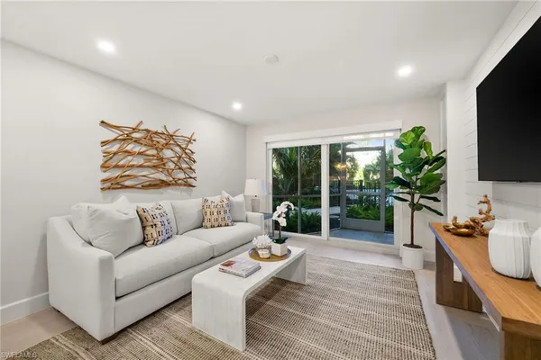 a living room with furniture a flat screen tv and a large window