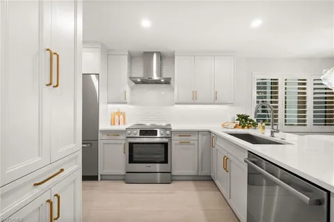 a kitchen with stainless steel appliances granite countertop a sink a stove a refrigerator and cabinets