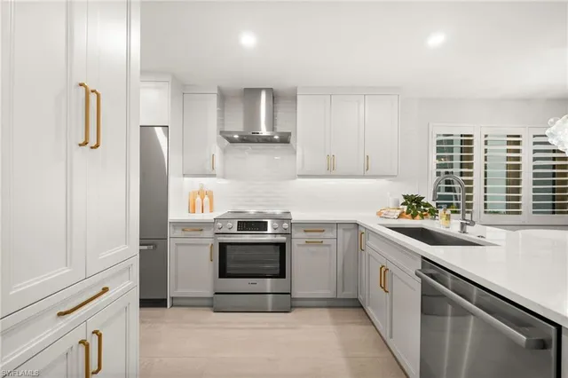 a kitchen with stainless steel appliances granite countertop a sink a stove a refrigerator and cabinets