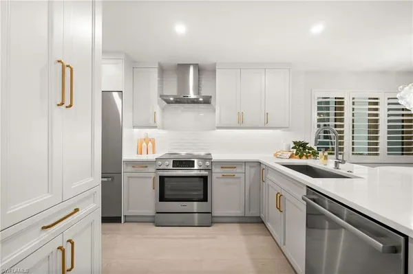 a kitchen with stainless steel appliances granite countertop a sink a stove a refrigerator and cabinets