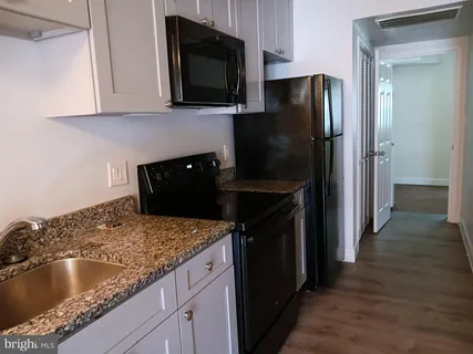a kitchen with granite countertop a refrigerator stove and microwave