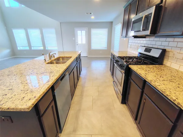 a kitchen with stainless steel appliances granite countertop wooden cabinets a stove top oven a sink and dishwasher