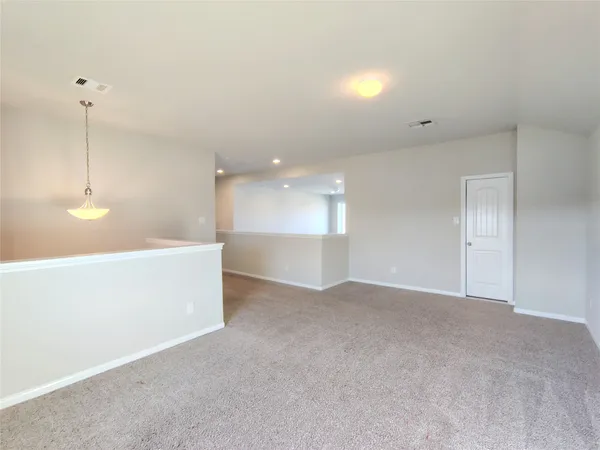 a view of an empty room with kitchen and a window