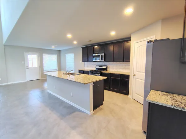 a large kitchen with kitchen island a sink a stove a refrigerator cabinets and a counter top space
