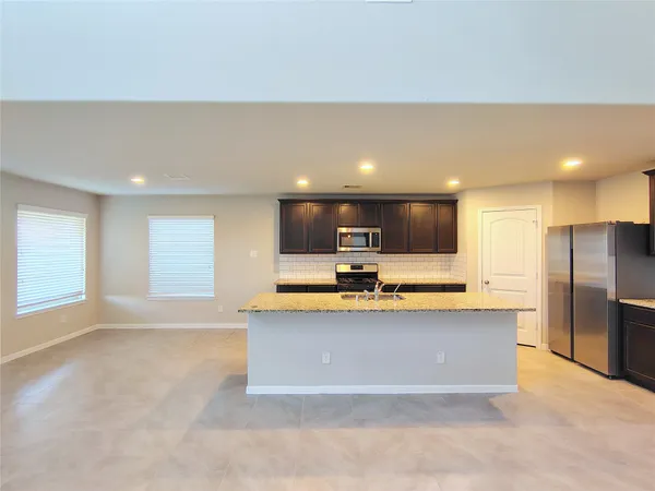 a view of kitchen with kitchen island a sink a stove and a refrigerator